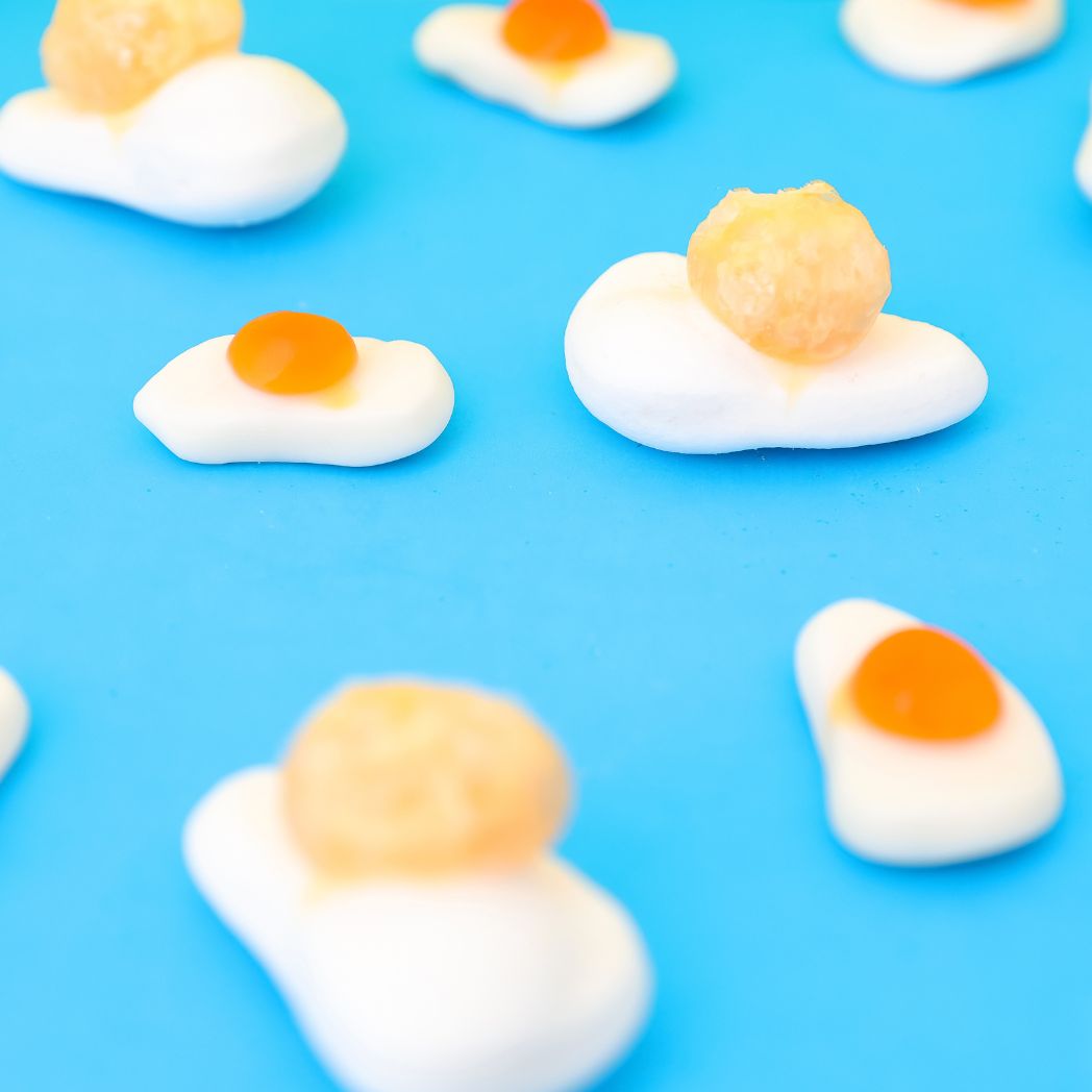 Fried egg-shaped candies with orange centers on a blue background