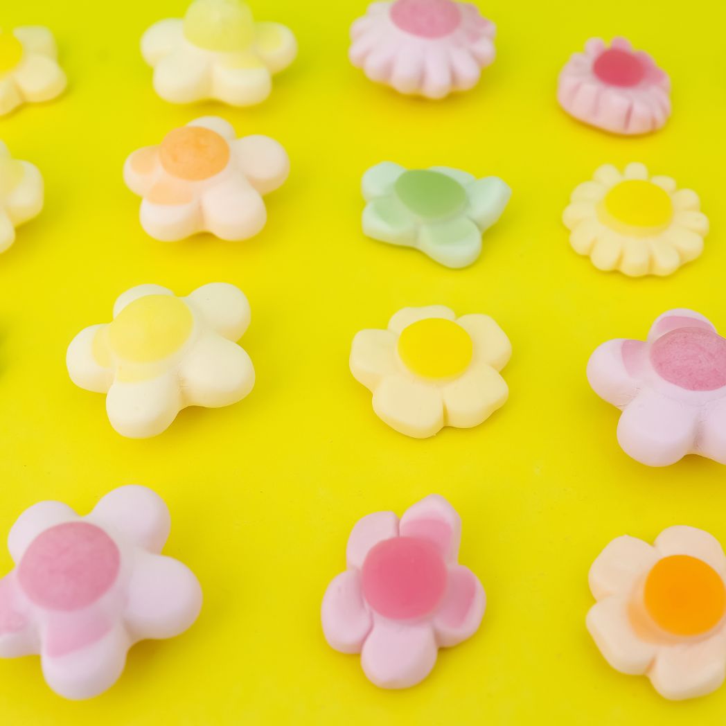 Flower-shaped candies in various colors on a yellow background