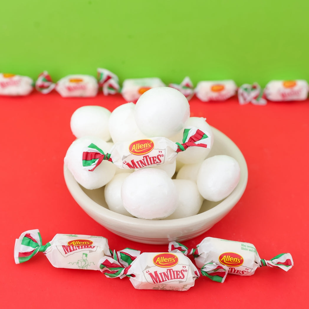 Bowl of Allen's Miniflies candy with wrapped candies on a red and green background