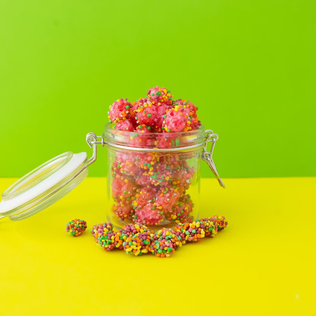 Jar of colorful gummy candies on a green and yellow background