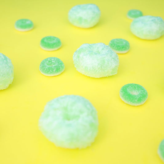 green freeze dried gummy apple rings on a yellow background