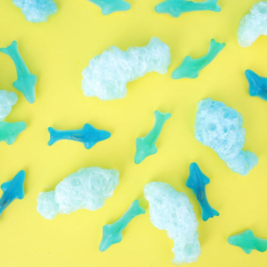 Pattern of blue and light blue shark-shaped bath bombs on a yellow background