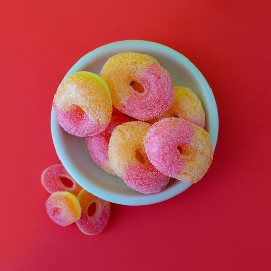 Colorful gummy candies in a white bowl on a red background