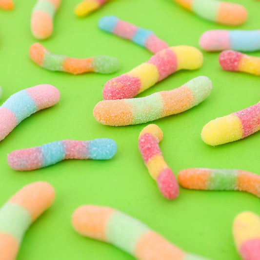 Colorful gummy worms on a green background