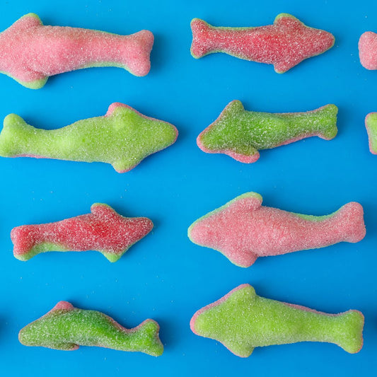 Colorful fish-shaped gummy candies on a blue background