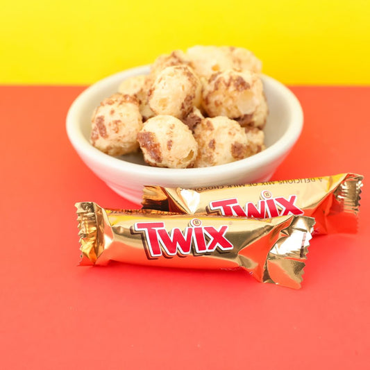 Twix candy bar with a bowl of cookies on a red and yellow background