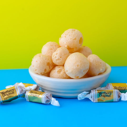 Bowl of orange candy balls with Werther's Original candy bars on a blue and green background